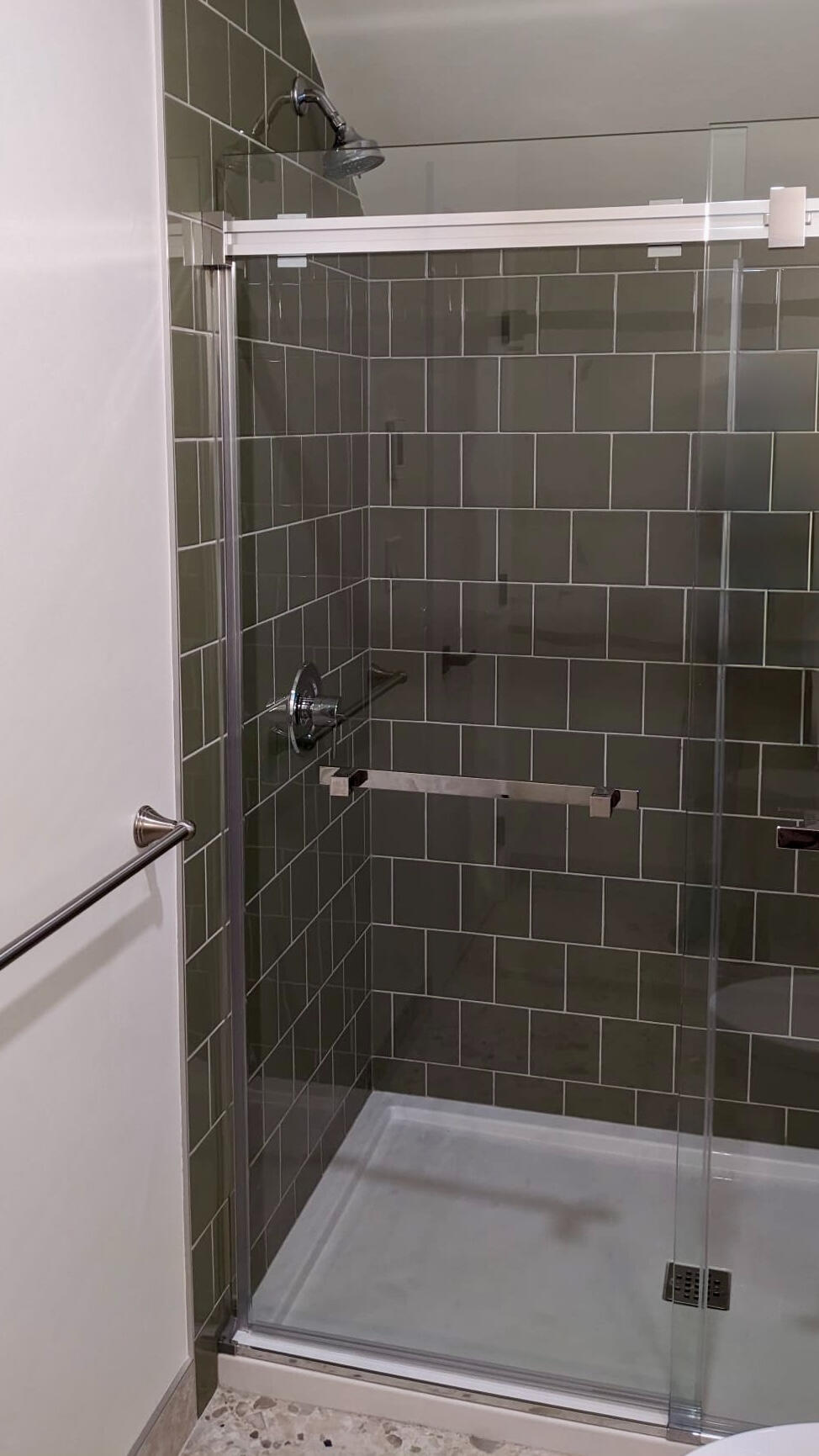 Modern Walk-In Shower with Sage Green Tile Custom walk-in shower featuring olive green subway tiles, sliding glass doors, and brushed nickel hardware
