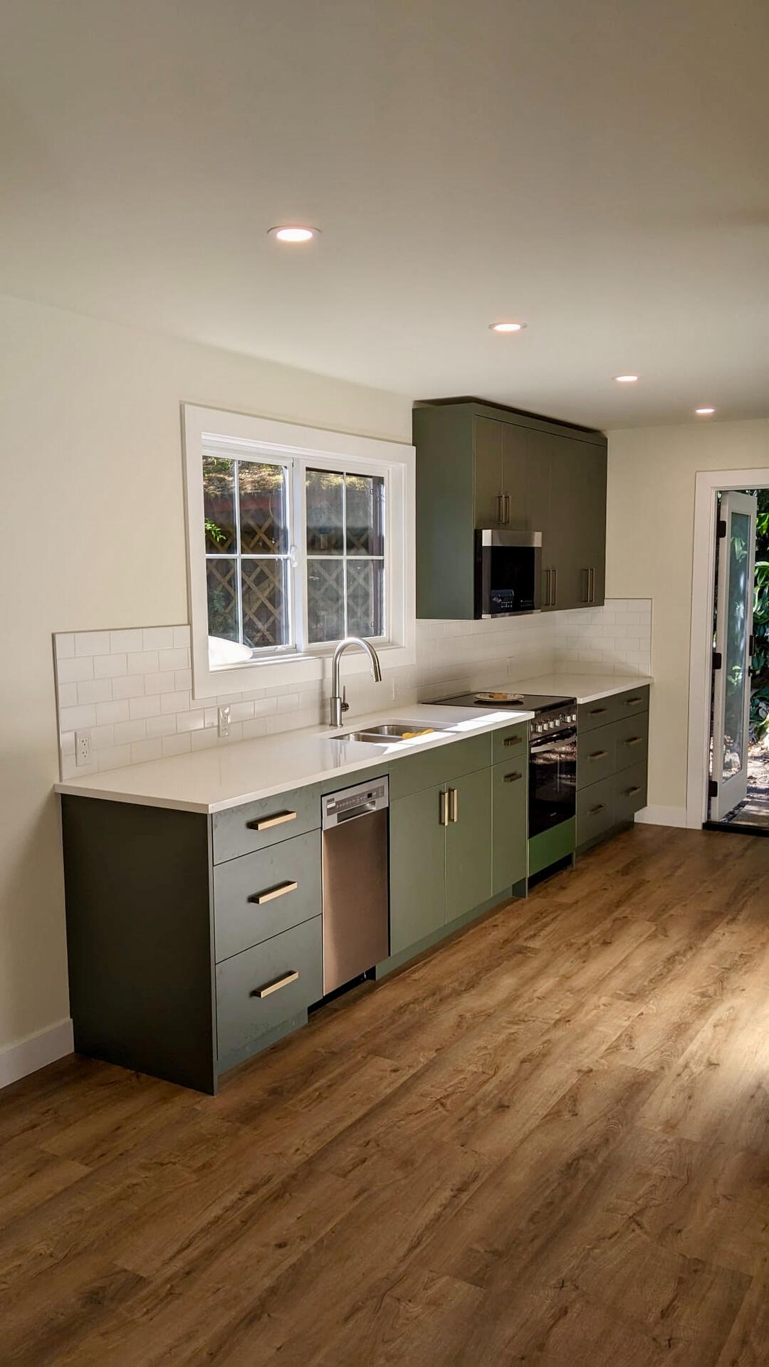 Custom Green Kitchen Cabinets & White Quartz Modern kitchen design featuring olive green lower cabinets, stainless steel appliances, white quartz countertops, and subway tile backsplash.