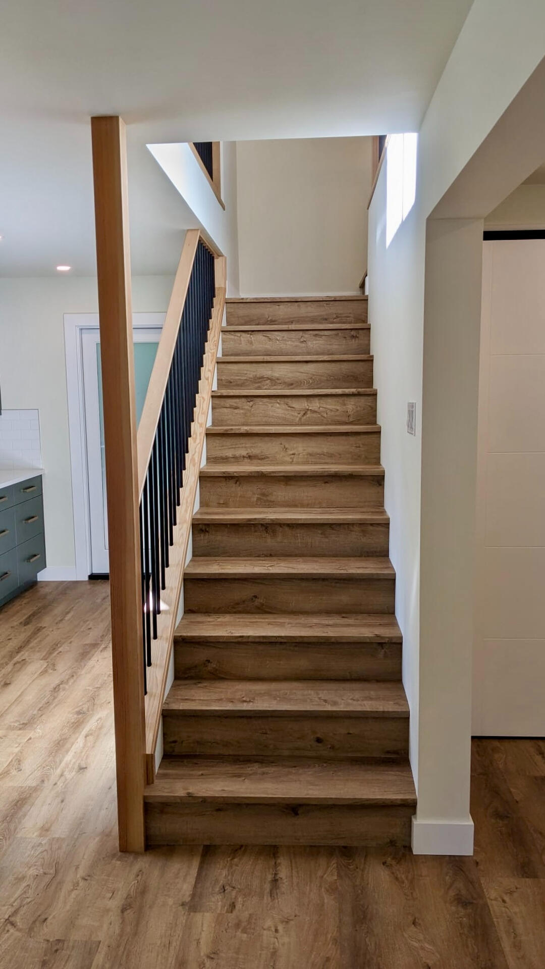 Straight Modern Staircase with Wood Treads Interior straight staircase with natural wood treads, white risers, and black iron balusters.